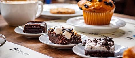 Una mesa con una taza de café, un muffin y tres platos de postres.