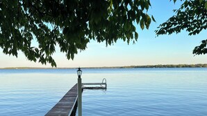 Eine hölzerne Pier, die sich in ruhiges Wasser erstreckt, umgeben von Wiesen und Bäumen.