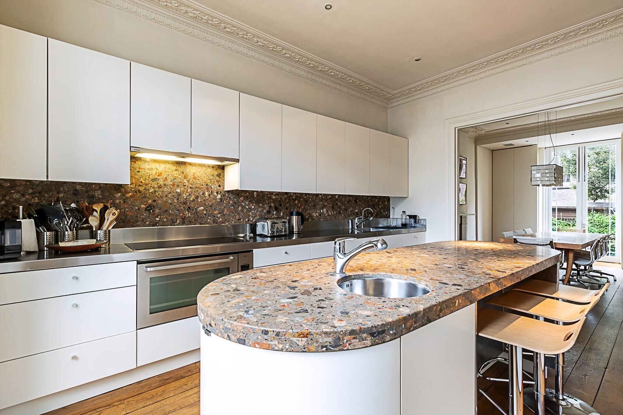 A modern kitchen with white cabinets, a granite countertop, and a built-in oven.