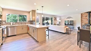Cocina moderna con una isla central, electrodomésticos integrados y grandes ventanales que ofrecen vistas al verdor.