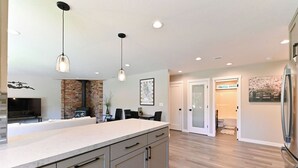 Una cocina moderna con una isla grande, iluminación colgante y una pared de ladrillo decorativa.
