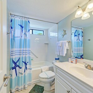 A bathroom with a bathtub, toilet, and sink. There is a shower curtain with a starfish design.