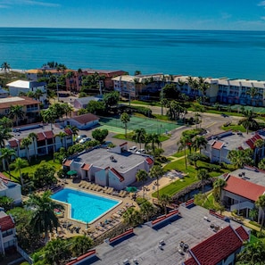 A resort with a swimming pool, tennis courts, and beachfront views.