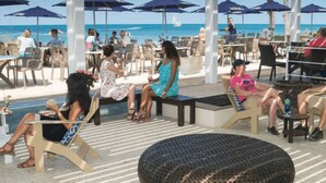 An outdoor seating area with tables and chairs, umbrellas, and a view of the ocean.