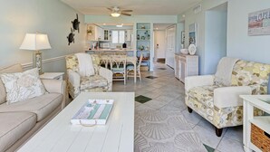 A spacious living room with a white coffee table, a sofa, and a dining area with a table and chairs.