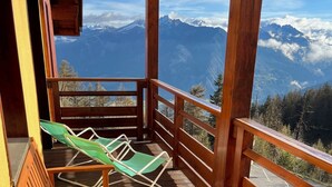 A wooden deck with a bench and two green lounge chairs, overlooking a mountainous landscape. - Risoul - Appartement de Standing - 6 Couchages (Risoul)