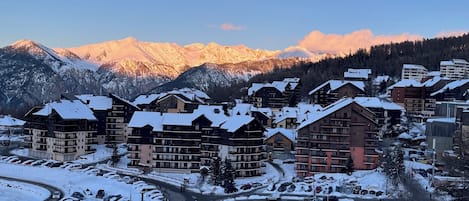 Et sneklædt feriested med flere chalet-lignende bygninger, stolelift og et bjerg i baggrunden.