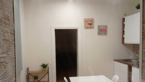 Una cocina compacta con una mesa blanca, una pequeña planta y una puerta que da a otra habitación.