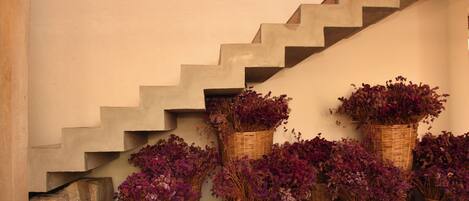 Una escalera con cestas de mimbre que contienen flores moradas.