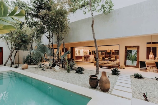 A modern outdoor living area with a pool, seating, and a dining space.