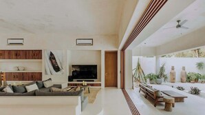 Una sala de estar moderna con un sofá, televisión y un comedor con mesa y sillas.