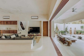 A modern living room with a sofa, TV, and a dining area with a table and chairs. - Casa Fuego Sanctuary Villa Private Chef Beach Club (Tulum)