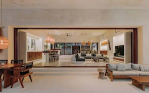A spacious living area with a dining table, sofas, and a TV.