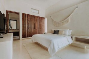 A modern bedroom with a bed, bedside tables, a hanging chair, and a wooden panel wall.