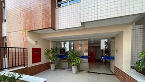 Un vestíbulo de hotel con suelo de baldosas, plantas en macetas y una recepción.