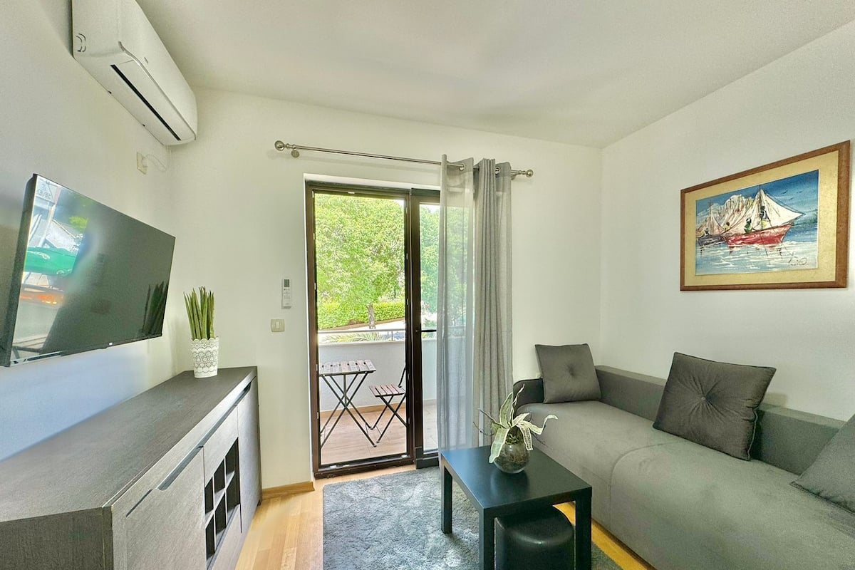 Una sala de estar moderna con un sofá, una mesa de centro, un televisor y un cuadro en la pared.
