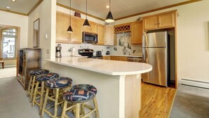 Una cocina con armarios de madera, un refrigerador de acero inoxidable, un microondas y una isla grande con taburetes de bar.