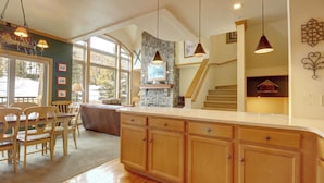 Una cocina amplia con armarios de madera, una pared decorativa de piedra y un ventanal que proporciona luz natural.