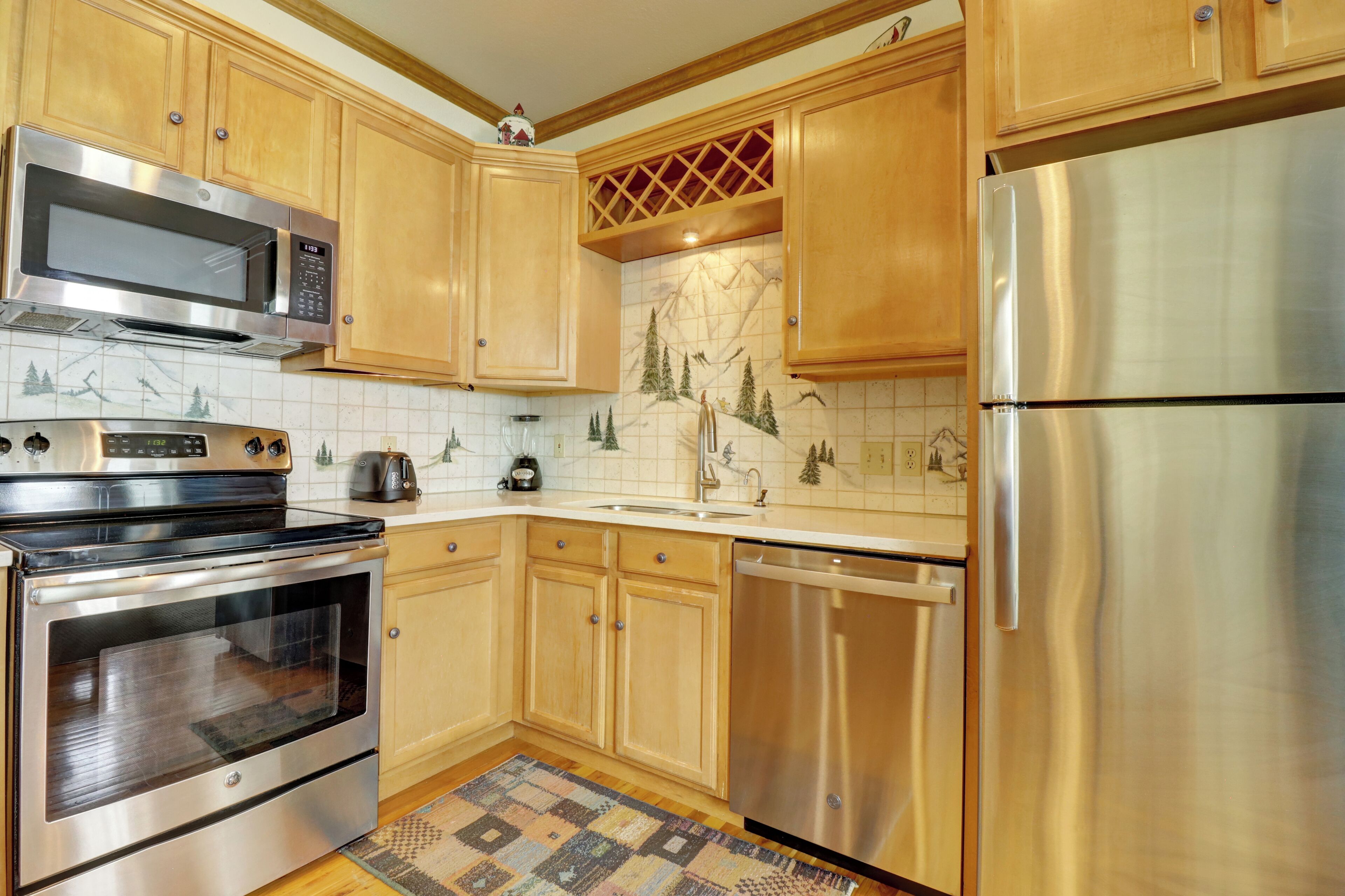 A kitchen with wooden cabinets, stainless steel appliances, and a patterned backsplash.