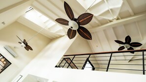 A modern interior with a high ceiling, multiple ceiling fans, and a staircase with a metal railing. - Una Villa Colonial con Encanto en el Corazón del Casco Antiguo (Panama)