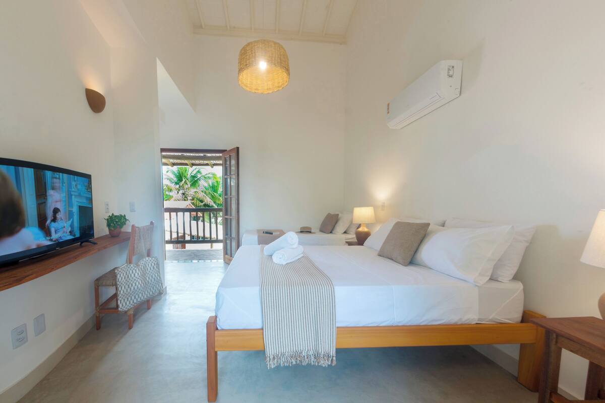 A bedroom with a bed, bedside tables, a TV, and a balcony with a view.