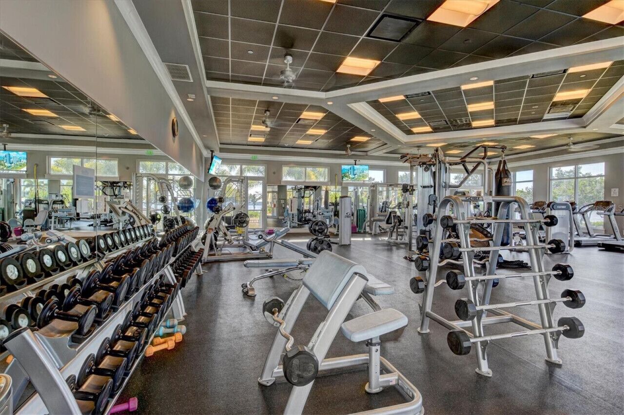 Un'ampia palestra con diverse attrezzature per l'allenamento, grandi finestre e soffitto alto.