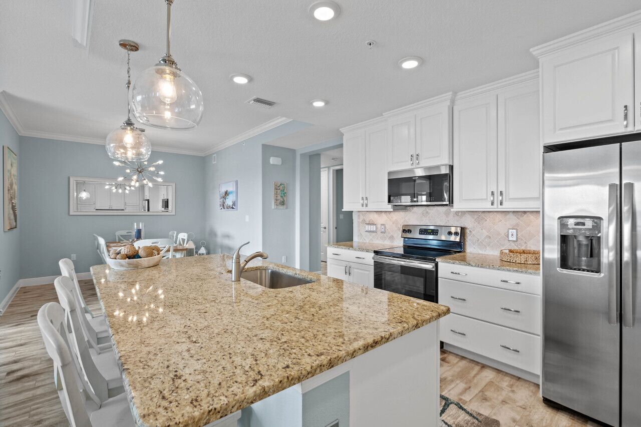 A modern kitchen with white cabinets, stainless steel appliances, and a granite countertop.