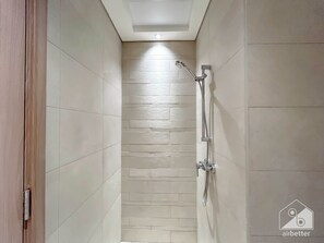 Un espacio de ducha estrecho con suelo de baldosas y un cabezal de ducha en la pared.