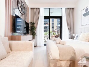 Habitación de hotel moderna con una cama grande, un sofá, un televisor y un balcón con una silla colgante.