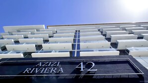 A hotel sign with the name "AZIZI RIVIERA 42" and a modern building with a grid of balconies. - Elegant Studio With Balcony on the Riviera Dubai (Dubai)