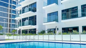 A modern building with a swimming pool in front. - Elegant Studio With Balcony on the Riviera Dubai (Dubai)
