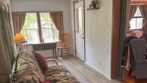 A room with a patterned sofa, a wooden chair, a desk, and a window with curtains. - Godin's Get A Way,  Creekside cabin, Relax in Murphy, NC.  Close to everywhere! (Murphy)