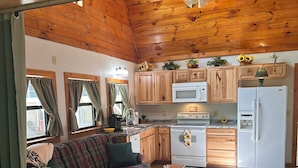 A cozy cabin-style interior with a wooden ceiling, a kitchenette, a plaid sofa, and a dining table. - Godin's Get A Way,  Creekside cabin, Relax in Murphy, NC.  Close to everywhere! (Murphy)