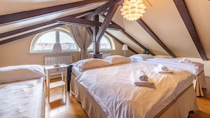 Un dormitorio acogedor en el ático, con una cama grande, un escritorio y un ventanal con vistas a edificios.