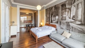Un dormitorio con una cama, un sofá, un escritorio y un mural en la pared.