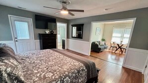 Une chambre dotée d’un grand lit, d’un ventilateur de plafond et donnant sur un coin repas.