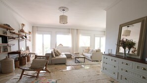 A spacious living room with a sofa, armchairs, a coffee table, and a large mirror. There are bookshelves and a fireplace. - Tess Villa Olmos in M Laga (Málaga)