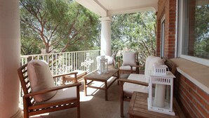 A balcony with wooden furniture, white cushions, and a lantern. - Tess Villa Olmos in M Laga (Málaga)