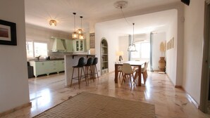 A spacious living area with a dining table, chairs, and a kitchen in the background. - Tess Villa Olmos in M Laga (Málaga)