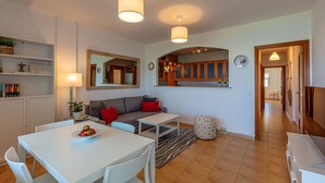 Ett modernt vardagsrum med soffa, matbord och köksdel.