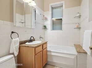 A modern bathroom with a sink, vanity, mirror, and bathtub. - West Town Wonder (Chicago)