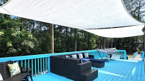 Una terrazza esterna riparata con ringhiere blu, mobili in vimini e un'amaca.