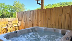 Un jacuzzi con una valla de madera y sillas al fondo.