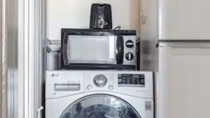 A compact laundry area with a washing machine, a microwave, and a refrigerator.