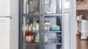 A kitchen with a built-in cabinet containing various kitchenware and dishes.