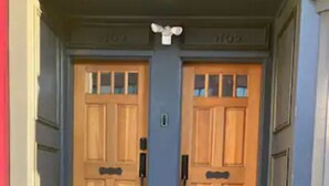 A double wooden door with a small window above it, flanked by two steps leading up to the door.