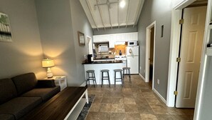 Una cocina moderna con armarios blancos, una isla central con taburetes y un comedor con banco y mesa.
