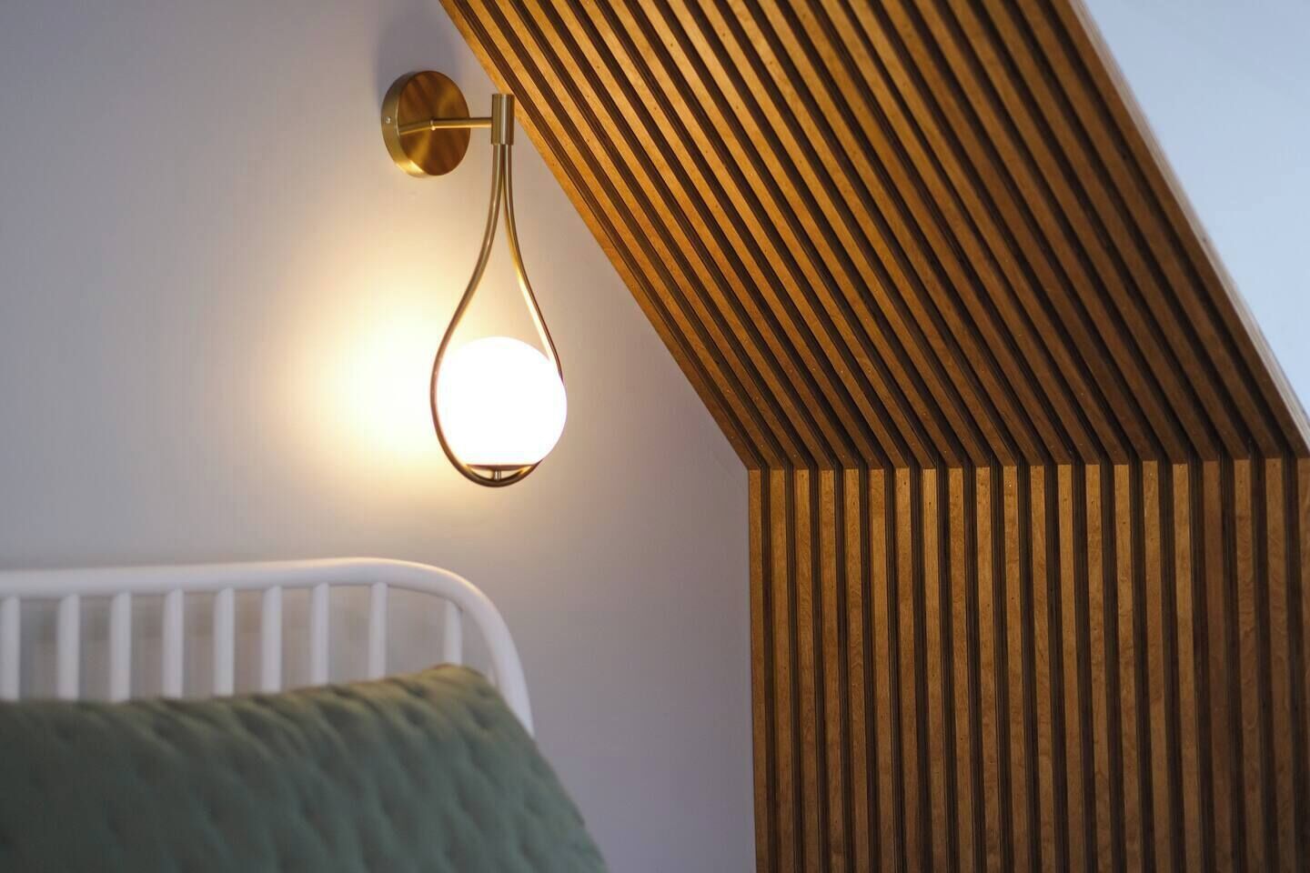 Une pièce avec un plafond en pente, un radiateur blanc et un luminaire fixé au mur.