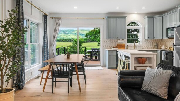 Une cuisine spacieuse avec un îlot central, un coin repas avec une table et des chaises, et un canapé en cuir noir.