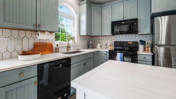 Une cuisine moderne avec des meubles de couleur bleu clair, un réfrigérateur en acier inoxydable, un four à micro-ondes noir et un lave-vaisselle.